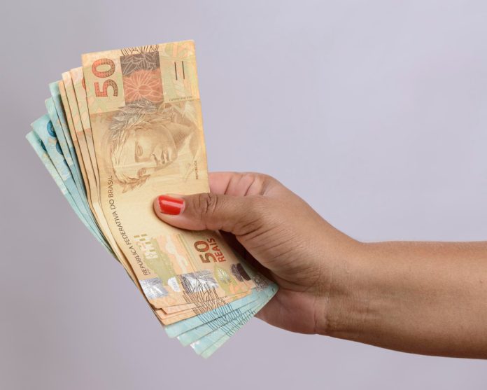 mao-segurando-o-dinheiro-seiscentos-reais-moeda-brasileira-no-fundo-branco (1)