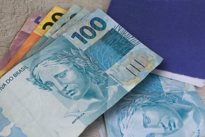 dinheiro-brasileiro-em-papel-e-caderno-em-superficie-de-madeira