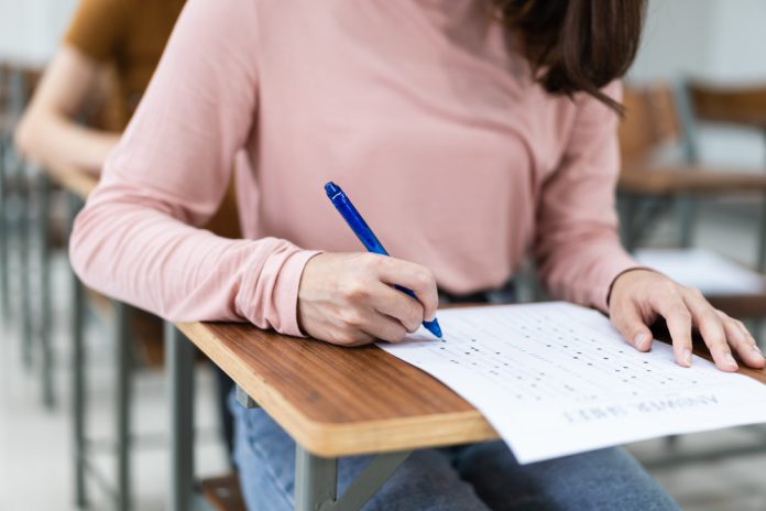 perto-de-jovens-estudantes-universitarias-concentre-se-em-fazer-o-exame-em-sala-de-aula-aluna-escreve-a-resposta-dos-exames-na-folha-de-respostas-da-sala-de-aula