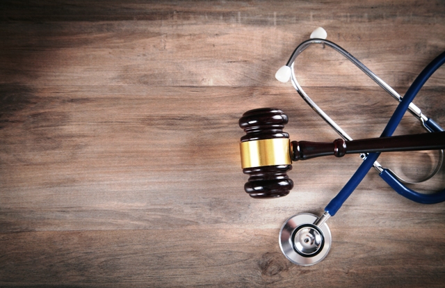 Judge gavel and stethoscope on the wooden table.